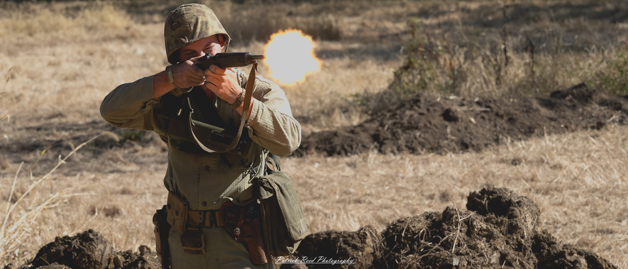 "Image of a soldier firing an M1 Carbine during World War II. The soldier is in a dynamic shooting position, with the carbine raised and aimed downrange. He is dressed in standard military gear, including a helmet and uniform typical of the era. The background features a battlefield setting, showcasing debris and the remnants of conflict. The action captures the intensity and urgency of combat, highlighting the soldier's focus and determination."